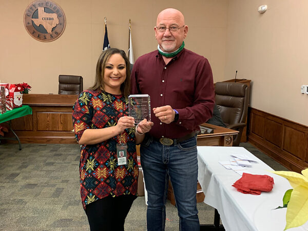 Samantha Bayfus (right) is presented with a plaque by Cuero City Manager Raymie Zella in recognition of her receipt of the City of Cuero 2020 Newton Rath Employee of the Year Award