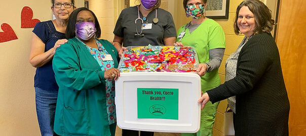 Photo of December Events Committee presenting “thank you” snack care package to Cuero Health