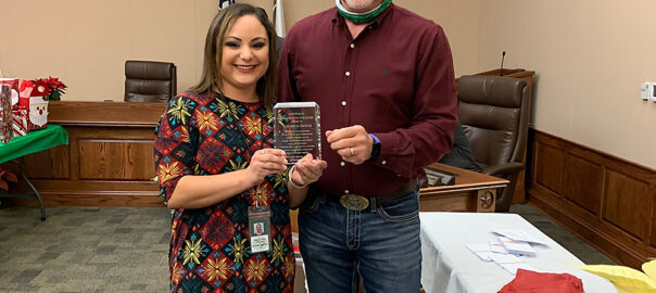 Samantha Bayfus (left) is presented with a plaque by Cuero City Manager Raymie Zella in recognition of her receipt of the City of Cuero 2020 Newton Rath Employee of the Year Award